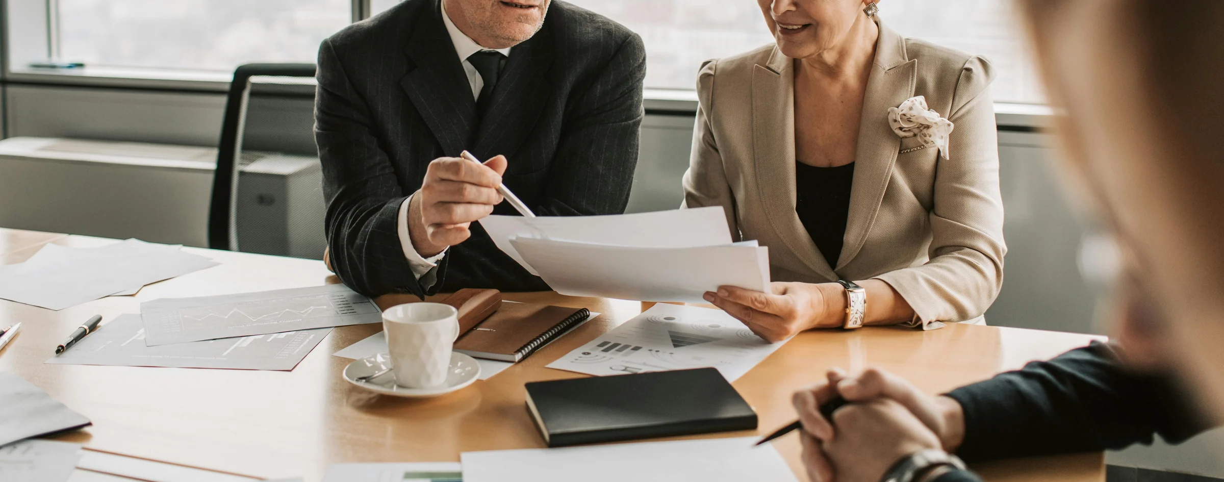 Dois executivos seniores analisando documentos de planejamento financeiro em uma sala de reunião.